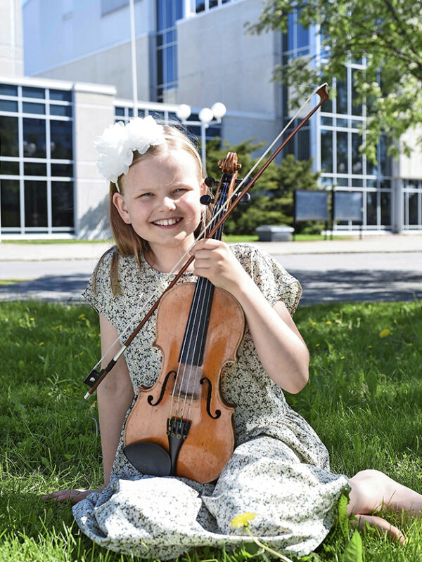 Viulisti Lilja Haatainen istuu viulunsa kanssa pihalla.