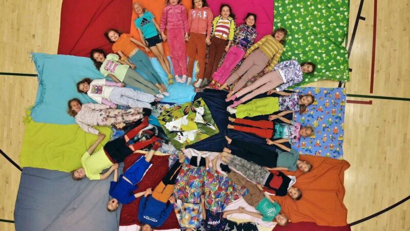 Reilu luokka värityskuva, oppilaat makaavat värikkäillä vilteillä värikkäissä vaatteissa.