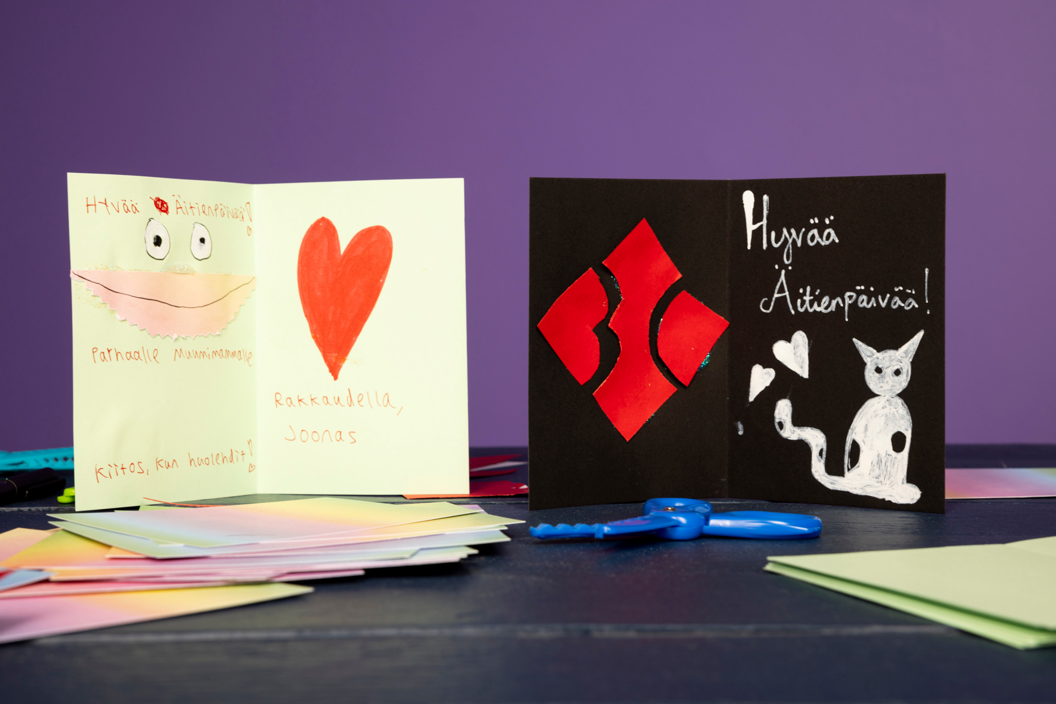 Blind Channel -muusikkojen valmiit kortit äideilleen. Joonaksen kortti on vaaleanvihreä ja siinä on punainen sydän. Kortissa lukee "Hyvää äitienpäivää parhaalle Muumimammalle. Kiitos kun huolehdit! Rakkaudella, Joonas." Nikon kortti on musta ja siinä on BC-logo sekä Rommi-kissa. Kortissa lukee "Hyvää äitienpäivää!"